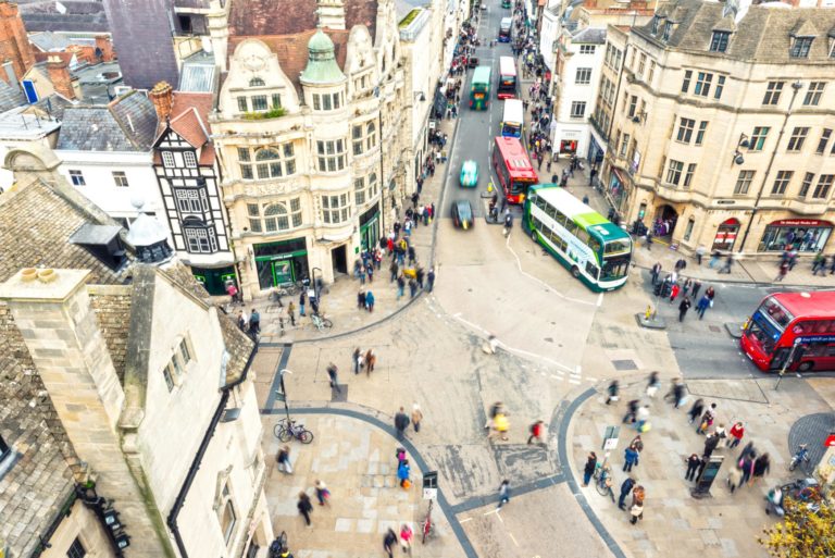 Oxford City, one of the most popular cities with universities in UK. Aerial view on the city crossroad - houses, people and busses.